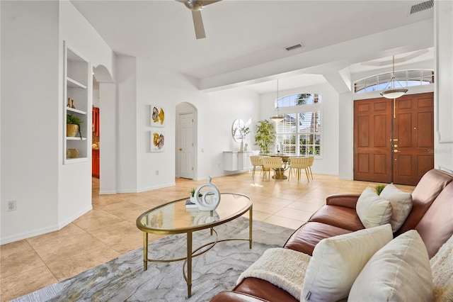 living area featuring arched walkways, built in shelves, light tile patterned flooring, and visible vents