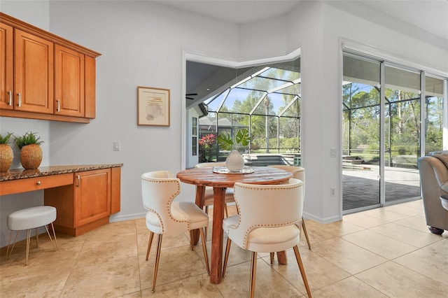 dining room with a sunroom, built in study area, baseboards, and light tile patterned floors