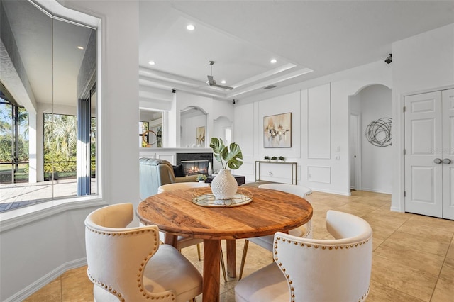 dining area featuring arched walkways, recessed lighting, a glass covered fireplace, ceiling fan, and baseboards