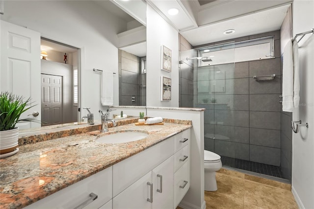 bathroom featuring toilet, tiled shower, and vanity