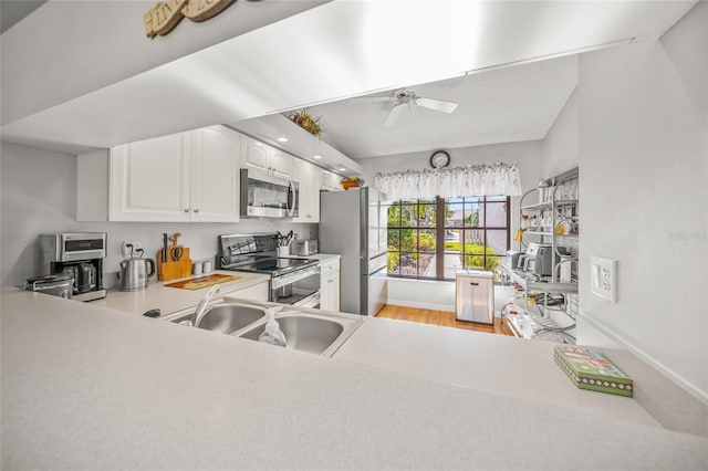 kitchen featuring lofted ceiling, sink, ceiling fan, stainless steel appliances, and white cabinets