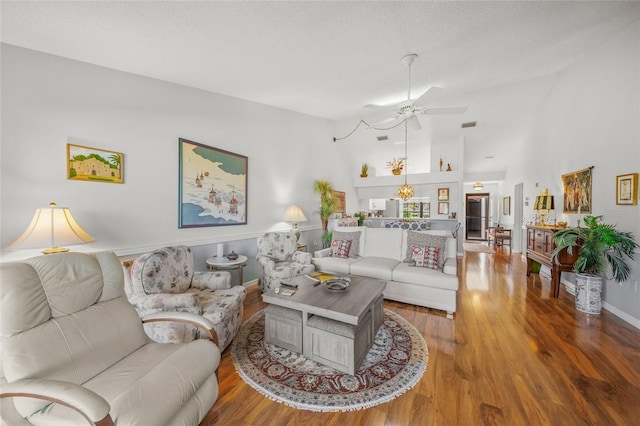 living room featuring ceiling fan, wood-type flooring, high vaulted ceiling, and a textured ceiling