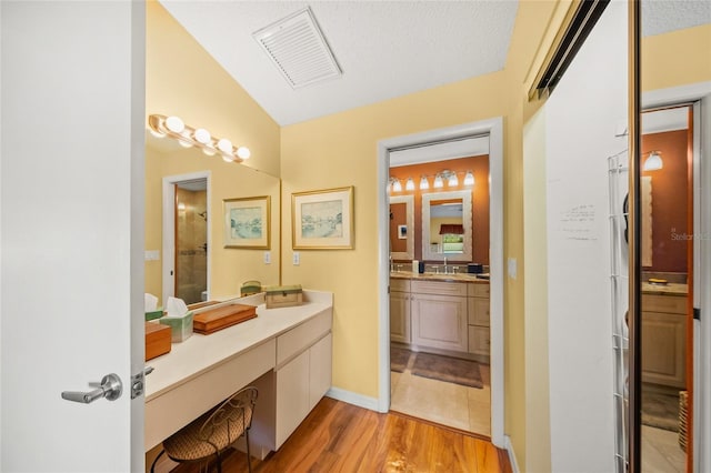 bathroom with vanity, vaulted ceiling, hardwood / wood-style floors, and walk in shower