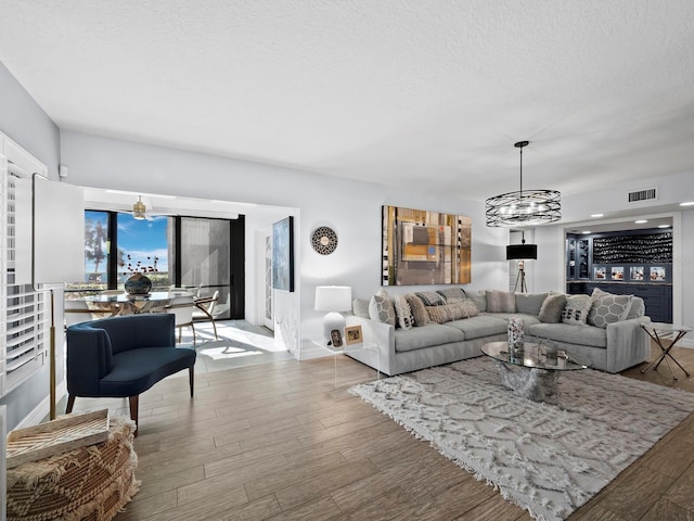 living room with an inviting chandelier, hardwood / wood-style flooring, and a textured ceiling