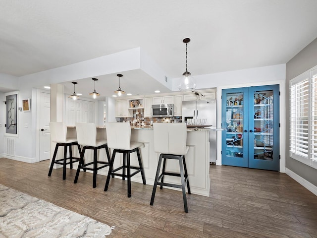 kitchen featuring pendant lighting, white cabinetry, a kitchen breakfast bar, and appliances with stainless steel finishes