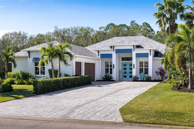 view of front of property featuring french doors, a garage, and a front lawn