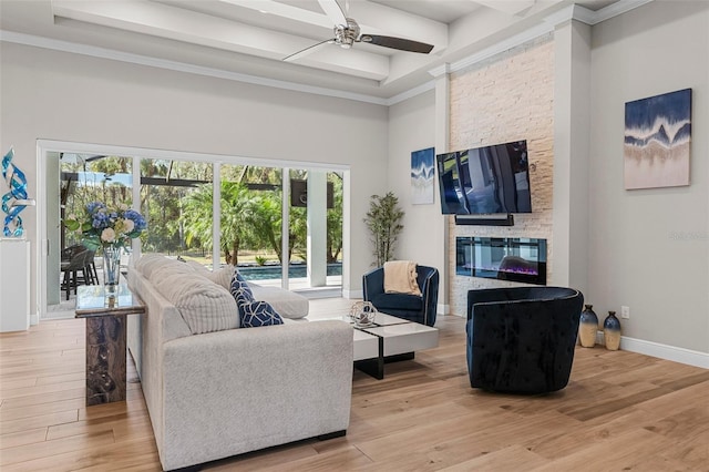 living room featuring beamed ceiling, ceiling fan, wood-type flooring, and a stone fireplace