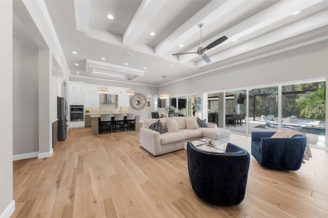 living room with ceiling fan, beam ceiling, and light hardwood / wood-style floors