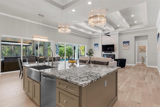 kitchen with hanging light fixtures, dishwasher, ceiling fan with notable chandelier, and a center island with sink