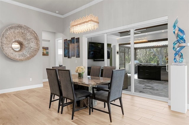 dining space with a notable chandelier, ornamental molding, a high ceiling, and light wood-type flooring