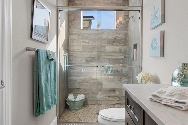 bathroom featuring vanity, toilet, and a shower with shower door