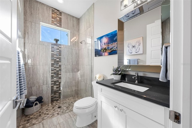 bathroom featuring a tile shower, vanity, and toilet