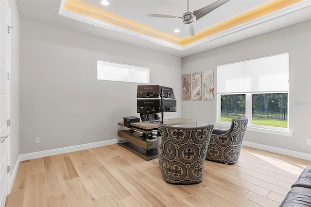 office space featuring a tray ceiling, ceiling fan, and light wood-type flooring