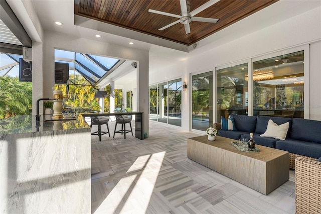 view of patio with an outdoor living space, ceiling fan, glass enclosure, and a bar