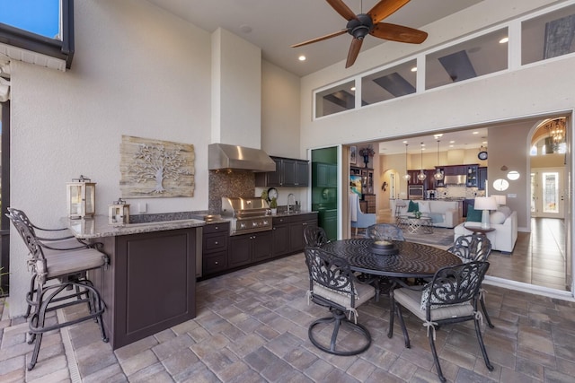 kitchen with sink, a breakfast bar area, light stone countertops, decorative backsplash, and kitchen peninsula