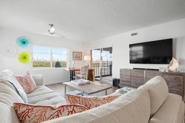 living room with ceiling fan, hardwood / wood-style floors, and a textured ceiling