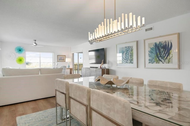 living room with ceiling fan, a textured ceiling, and light wood-type flooring