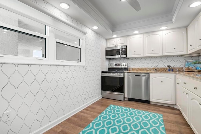 kitchen featuring white cabinetry, crown molding, light hardwood / wood-style flooring, and appliances with stainless steel finishes