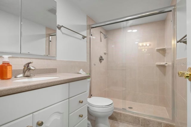 bathroom featuring tile walls, vanity, toilet, and walk in shower