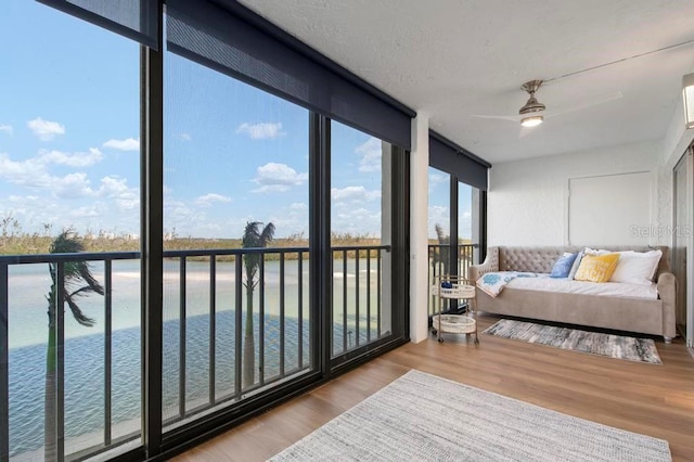 sunroom with ceiling fan and a water view