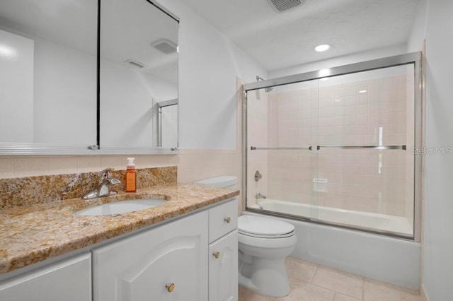 full bathroom with vanity, tile patterned flooring, bath / shower combo with glass door, and toilet