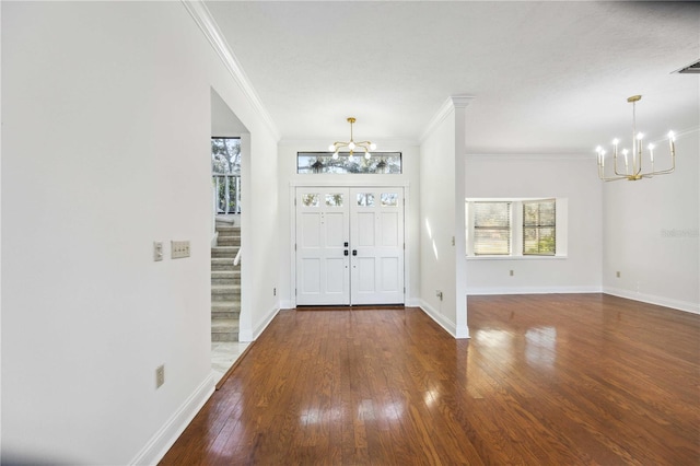 entryway featuring an inviting chandelier, dark wood-type flooring, and ornamental molding