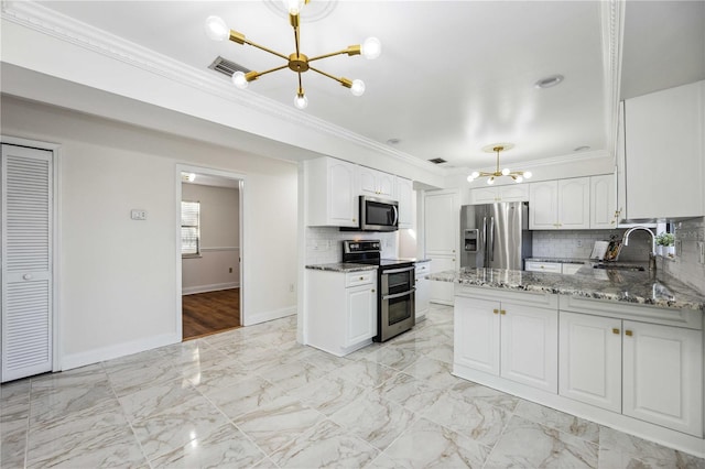 kitchen with sink, white cabinetry, dark stone countertops, appliances with stainless steel finishes, and a notable chandelier