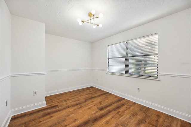 spare room with a notable chandelier and hardwood / wood-style flooring