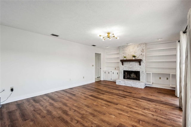 unfurnished living room featuring dark hardwood / wood-style floors, a fireplace, and built in shelves