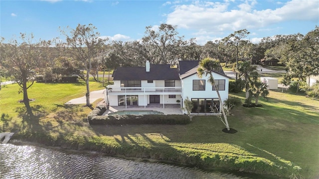 rear view of property featuring a lawn, a patio, a balcony, and a water view