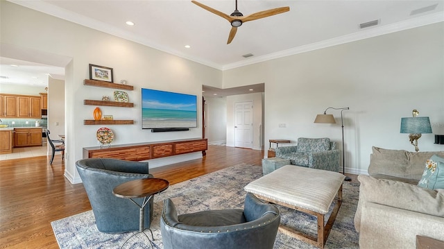 living room with crown molding, light hardwood / wood-style floors, and ceiling fan