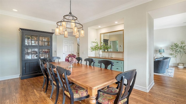 dining area with an inviting chandelier, ornamental molding, and wood-type flooring