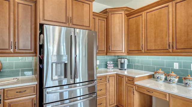 kitchen featuring tasteful backsplash, light stone counters, and stainless steel fridge with ice dispenser