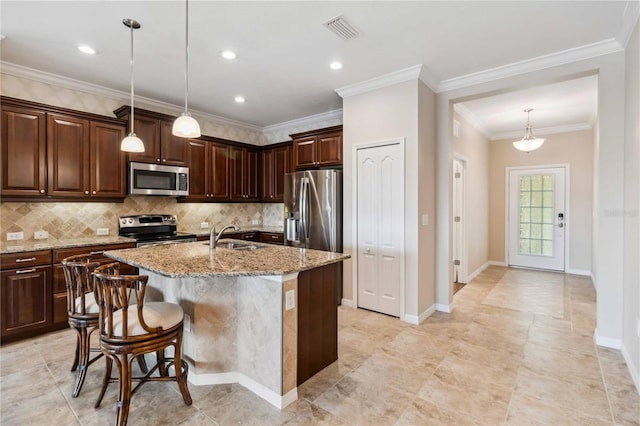 4891 Maymont Park Cir, Bradenton, FL 34203 - kitchen featuring pendant lighting, an island with sink, light stone counters, dark brown cabinetry, and stainless steel appliances