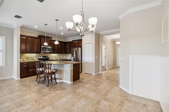 4891 Maymont Park Cir, Bradenton, FL 34203 - kitchen featuring appliances with stainless steel finishes, decorative light fixtures, a kitchen bar, light stone countertops, and a center island with sink