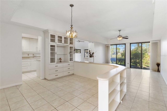 kitchen with ceiling fan with notable chandelier, pendant lighting, white cabinets, light tile patterned floors, and kitchen peninsula