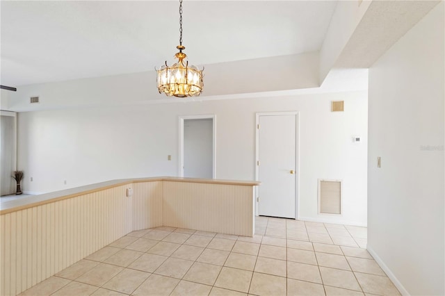 tiled empty room featuring an inviting chandelier