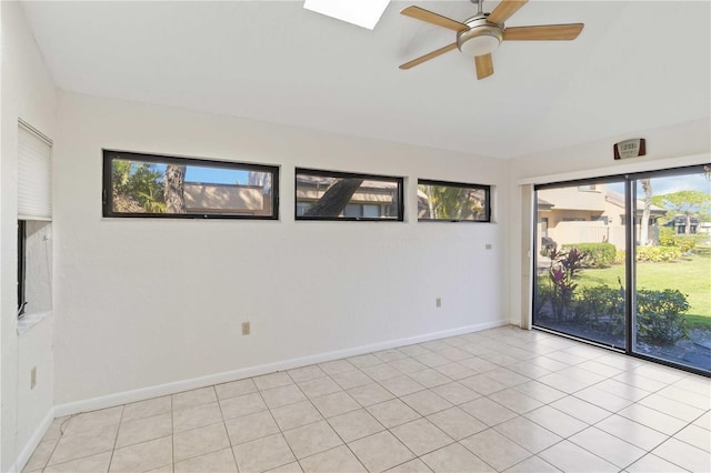 spare room with light tile patterned floors, ceiling fan, and a skylight