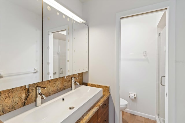 bathroom featuring vanity, a shower with shower door, and toilet