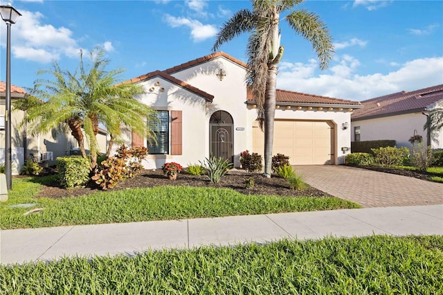 mediterranean / spanish-style house with a garage, a tile roof, decorative driveway, and stucco siding