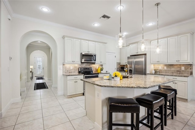 kitchen featuring arched walkways, visible vents, appliances with stainless steel finishes, ornamental molding, and light stone countertops