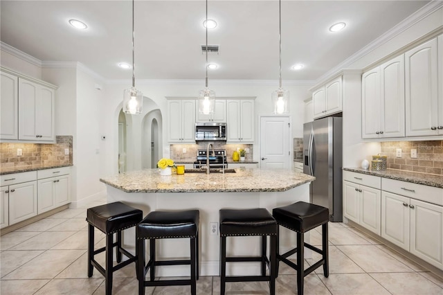 kitchen featuring appliances with stainless steel finishes, arched walkways, a sink, and light tile patterned floors