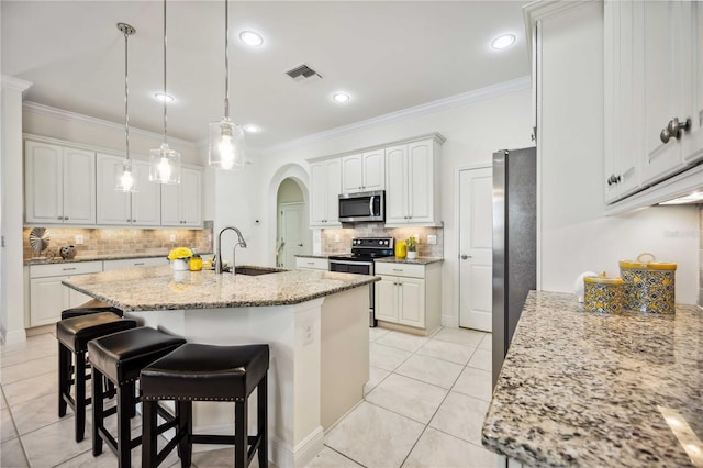 kitchen featuring arched walkways, stainless steel appliances, a sink, white cabinetry, and crown molding