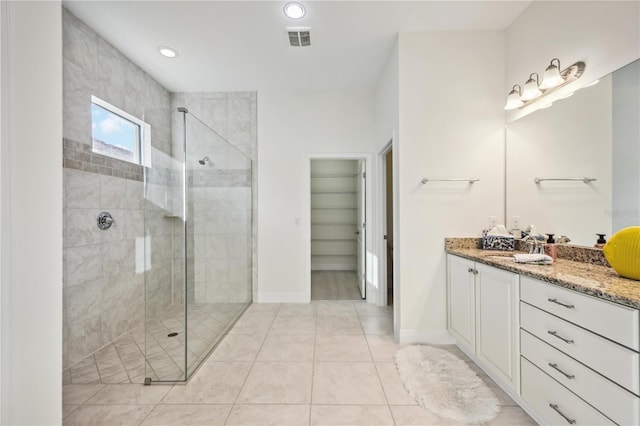 bathroom with a stall shower, a walk in closet, visible vents, and vanity