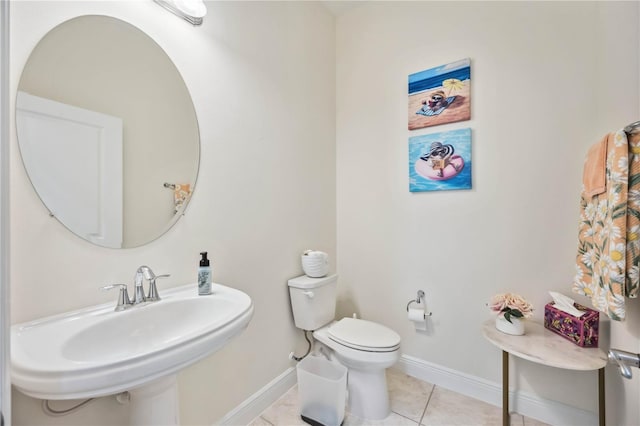 half bath with baseboards, a sink, toilet, and tile patterned floors