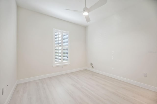 spare room featuring light wood-style flooring, a ceiling fan, and baseboards