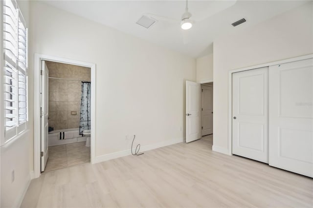 unfurnished bedroom with ceiling fan, light wood-style flooring, baseboards, a closet, and ensuite bath