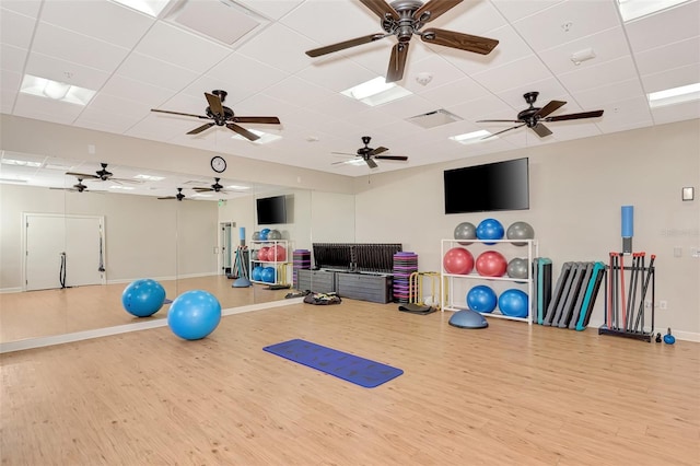 exercise room featuring a paneled ceiling, visible vents, baseboards, and wood finished floors