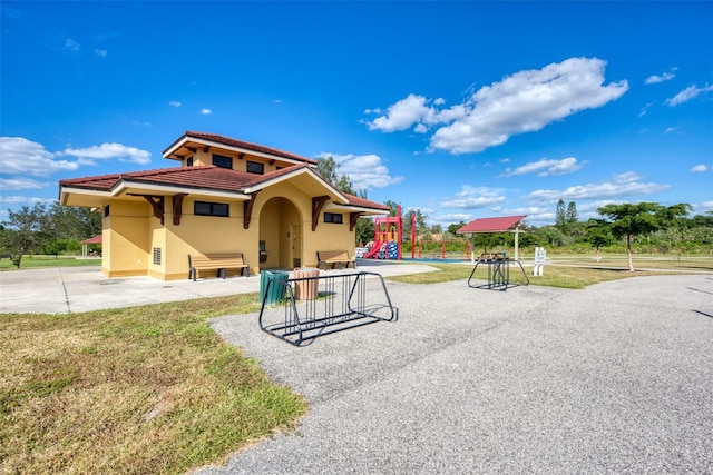 view of front of house featuring a tile roof, playground community, and stucco siding