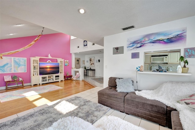 living room with tile patterned flooring, visible vents, and a textured ceiling